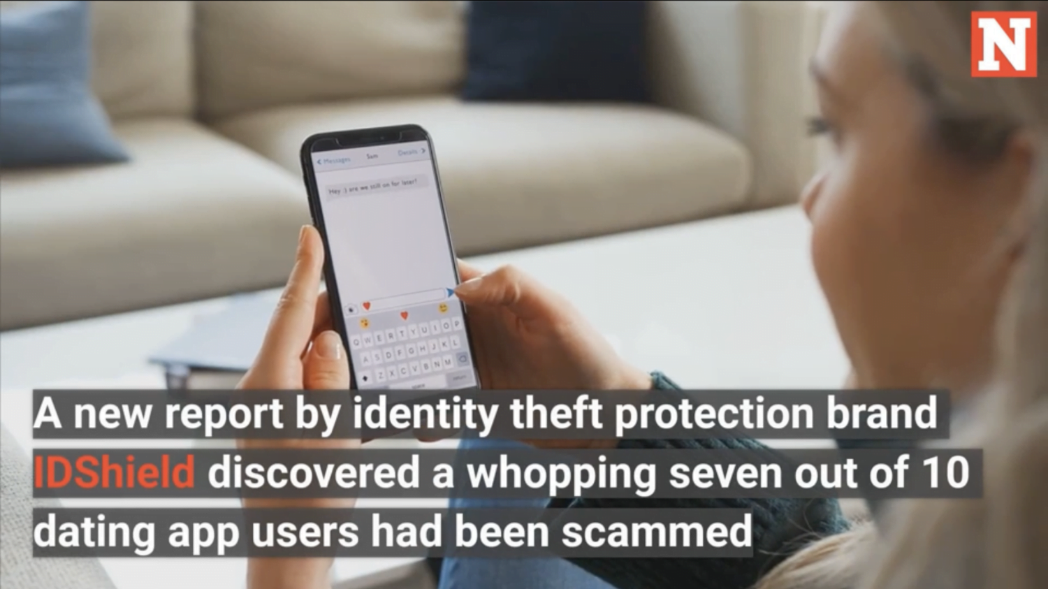 Woman holding her phone with text "a new report by identity theft protection brand IDShileld discovered a whopping seven out of ten dating app users had been scammed.